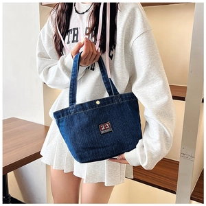Détails du sac cabas en denim bleu marine avec broderie rouge et bouton pression