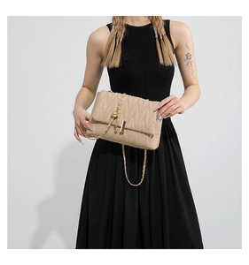 Close-up of beige quilted PU leather crossbody bag with gold chain and metal clasp detail
