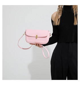 Detail of pink leather small square bag featuring a gold metal lock and shoulder strap
