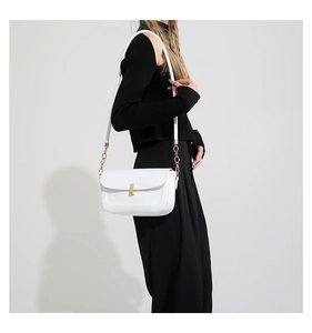 Detail of white PU leather crossbody bag with golden metal lock and chain strap on a model