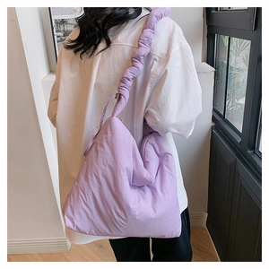 Détail du sac nuage lavande avec bandoulière froncée sur un modèle au style décontracté
