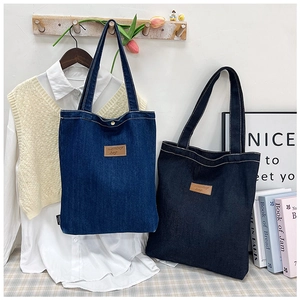 Détail de cabas en denim tendance bleu foncé et noir avec étiquettes en cuir marron