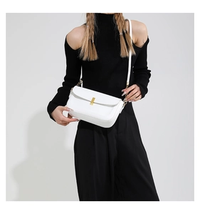 Detail view of white leather crossbody bag with elegant gold buckle and chain strap
