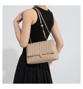 Detail of beige quilted PU crossbody bag with elegant gold chain and metallic ball accents