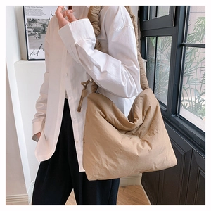 Détails de la texture matelassée et de la bandoulière plissée sur le sac en nylon kaki