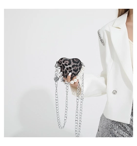 Detail of heart-shaped leopard print crossbody bag with silver chain and pearl handles