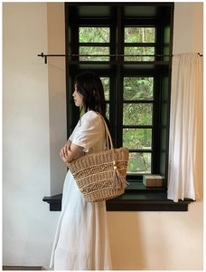 Gros plan d'un sac cabas en paille tressée beige avec pompons et perles en bois