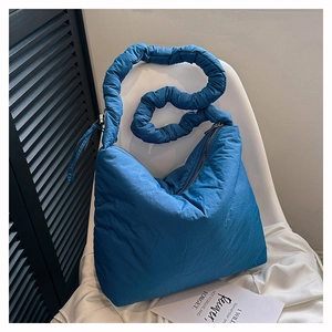 Sac bandoulière bleu en nylon matelassé design nuage avec bandoulière froncée sur chaise