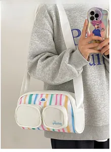 Close-up of white nylon shoulder bag with colorful stripes and functional double front pockets