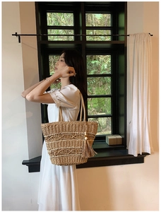 Vue détaillée du sac cabas en paille tressée avec pompons à franges sur un mannequin