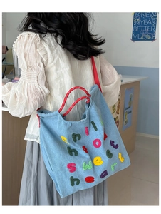 Dettaglio borsa tote in denim azzurro con ricami in spugna colorata e manici in corda