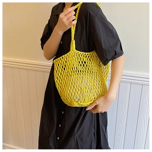 Detail of a bright yellow woven net handbag with a beige inner pouch and knot texture