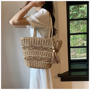 Gros plan sur un sac en paille tissé à la main avec motif creux et détail de pompon