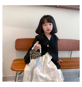 Detail of girls fashion set featuring black blazer and white embroidered tiered skirt