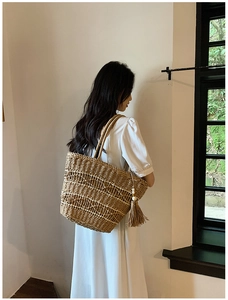 Gros plan sur un sac cabas en paille tressée avec pompon long et texture naturelle