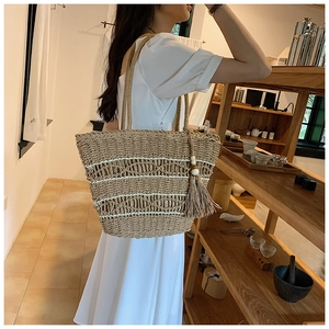 Détail du sac cabas en paille tissé avec motifs de vagues en coton et pompon