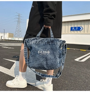 Close-up of a washed denim tote bag featuring white logo print and dual strap design
