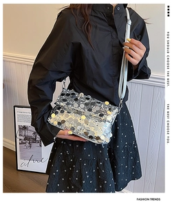 Close-up of a silver sequin crossbody bag styled with a sleek black outfit and floral skirt