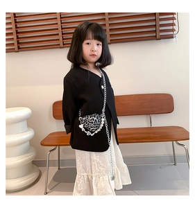 Detail of child wearing heart-shaped leopard print crossbody bag with pearl chain