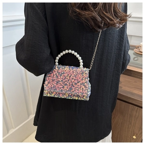 Detailed close-up of a colorful sequin handbag featuring a white pearl handle and metal chain