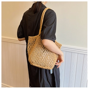 Detail of hand-woven straw tote bag with intricate mesh pattern and light brown finish