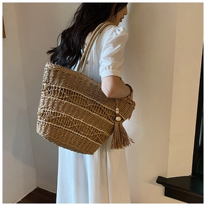 Détail d'un sac à bandoulière en paille tressée main avec glands en perles de bois et style bohème