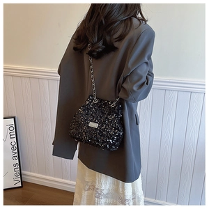 Detail of black sequined bucket bag with silver chain strap and metal logo plate