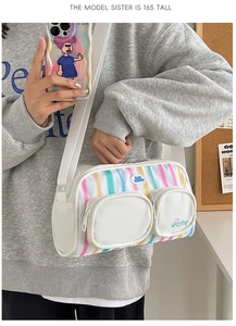 Detail of nylon crossbody bag with colorful rainbow stripes and dual front zip pockets