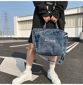 Detail of retro washed denim tote bag featuring white logo and adjustable shoulder strap