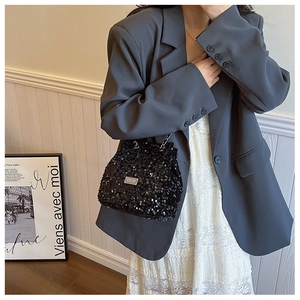 Close-up of black sequined bucket bag with silver metal logo and reflective texture