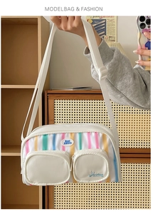 Detailed view of white nylon shoulder bag with colorful vertical stripes and dual front pockets