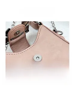 Close-up of pink PU leather bag featuring a round metal magnetic snap and chain link detail