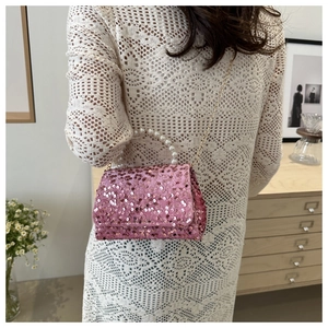 Close-up of pink sequin mini bag with white pearl handle and gold chain strap