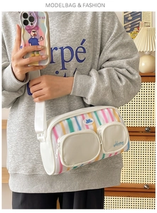Detail of white nylon shoulder bag with colorful vertical stripes and dual zipper pockets