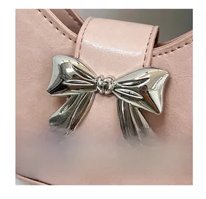 Detail of pink PU leather bag featuring a polished silver metal bow ornament buckle