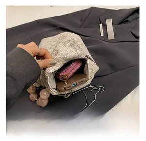 Vue macro de l'intérieur du sac en paille montrant le rangement du téléphone et du portefeuille