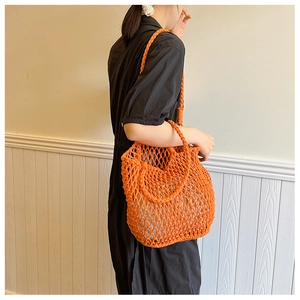 Close-up of bright orange hand-woven crochet mesh tote bag with chunky rope texture