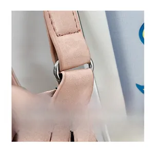 Close-up of pink PU leather bag detail showing polished silver metal ring and stitching