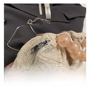 Détail macro du sac en paille tressée avec zip argenté et poignée en perles roses