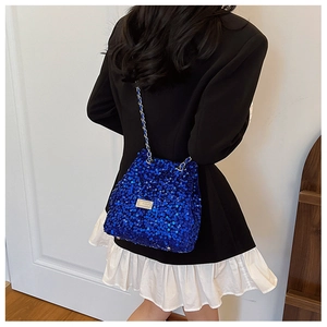 Close-up of blue sequin bucket bag with silver chain strap worn over a black blazer