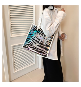 Chic holographic zebra print tote bag shown on shoulder with follow your dreams slogan