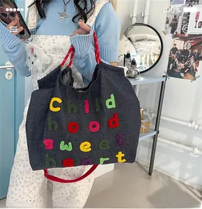 Dettaglio borsa tote in denim grigio con ricamo Childhood Sweetheart colorato e manici rossi