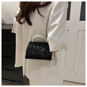 Detail of black sequined handbag with white faux pearl handle and gold chain strap