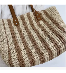 Close-up of woven straw tote bag with brown leather handles and vertical stripe pattern
