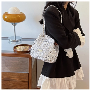 Close-up of sparkling silver sequin crossbody bag with elegant metal chain strap and logo