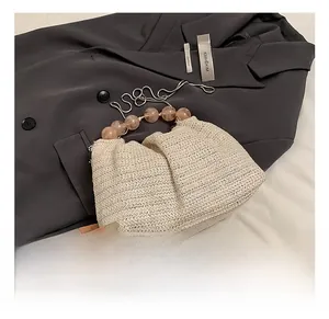 Détail du sac en paille tressée crème avec poignée en perles roses et chaîne fine