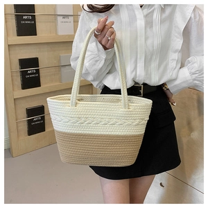 Detail of a two-tone woven tote bag featuring cream cable knit and khaki textures