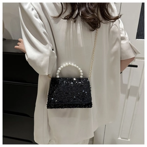 Detail of black sequin handbag with pearl handle and gold chain strap on shoulder