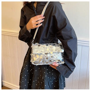 Detail view of silver sequin crossbody bag texture with metallic flap and shoulder strap