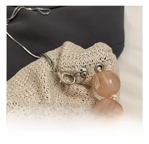 Détail du crochet métallique argenté et perle de résine sur un sac tissé en paille